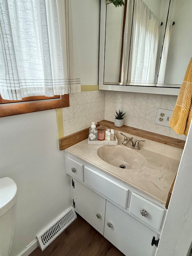 bathroom featuring vanity, hardwood / wood-style floors, backsplash, and toilet