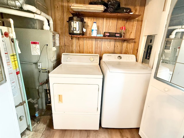 washroom with washer and dryer, hardwood / wood-style flooring, wooden walls, and water heater