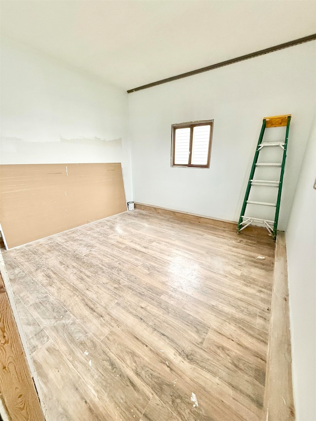 empty room with hardwood / wood-style flooring and crown molding