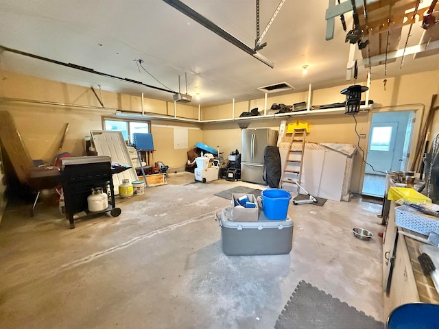 garage with stainless steel fridge and a garage door opener