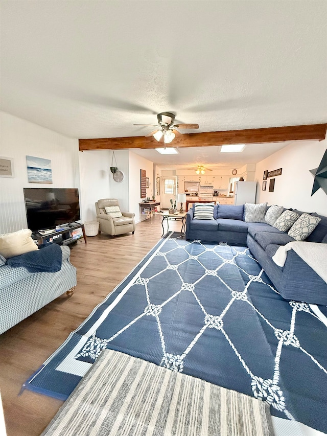 living room with beamed ceiling, ceiling fan, and wood-type flooring