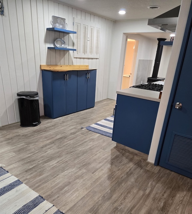 kitchen featuring wooden counters, hardwood / wood-style floors, a textured ceiling, and wooden walls