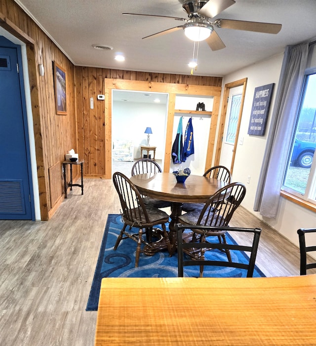 dining space with wooden walls, ceiling fan, and wood-type flooring