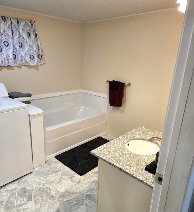 bathroom with vanity, a bathtub, and washer / clothes dryer