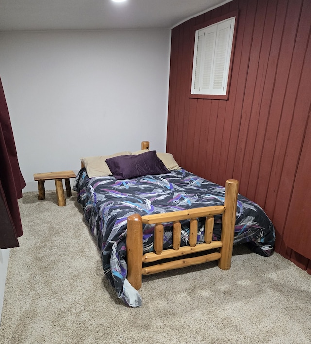 carpeted bedroom featuring wood walls