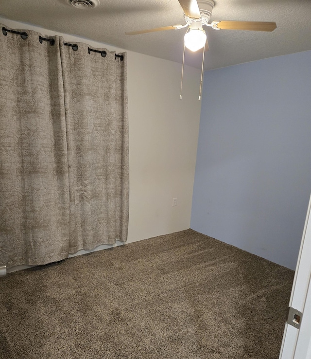 empty room with ceiling fan, carpet floors, and a textured ceiling