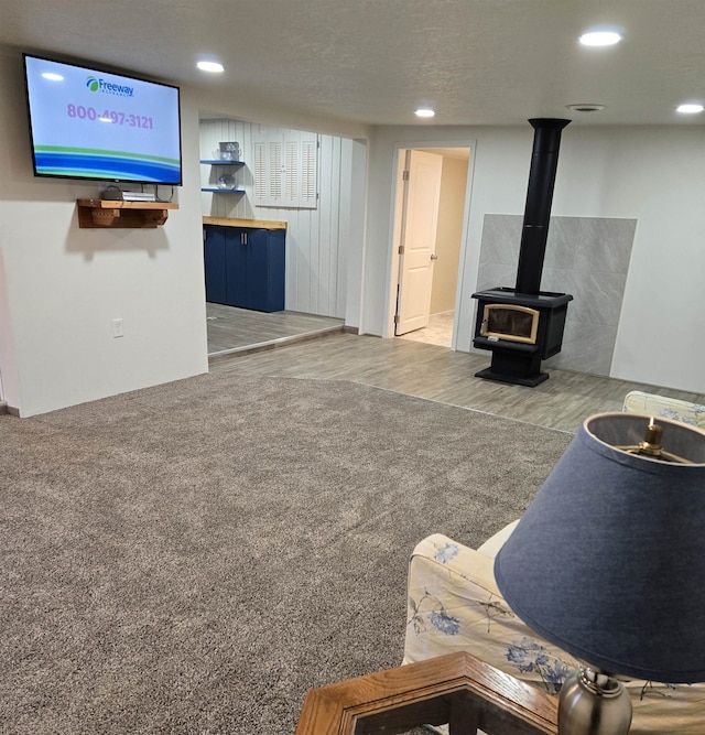 unfurnished living room featuring a wood stove, wood-type flooring, and a textured ceiling