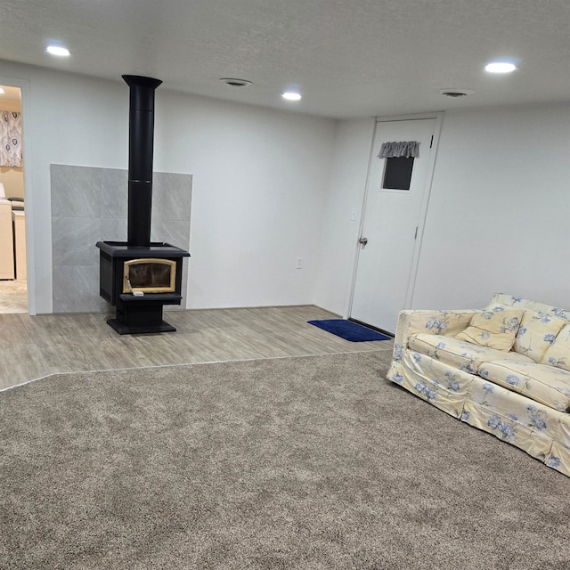 living room featuring wood-type flooring, a textured ceiling, and a wood stove