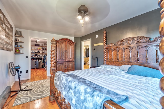 bedroom featuring light wood-type flooring, a walk in closet, ceiling fan, connected bathroom, and a closet