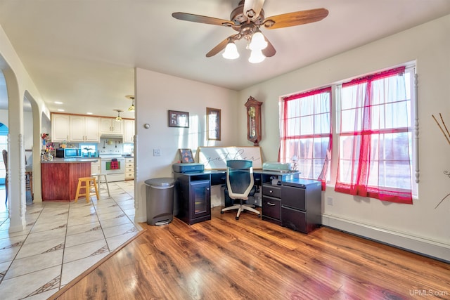 home office featuring ceiling fan, a baseboard heating unit, and light wood-type flooring