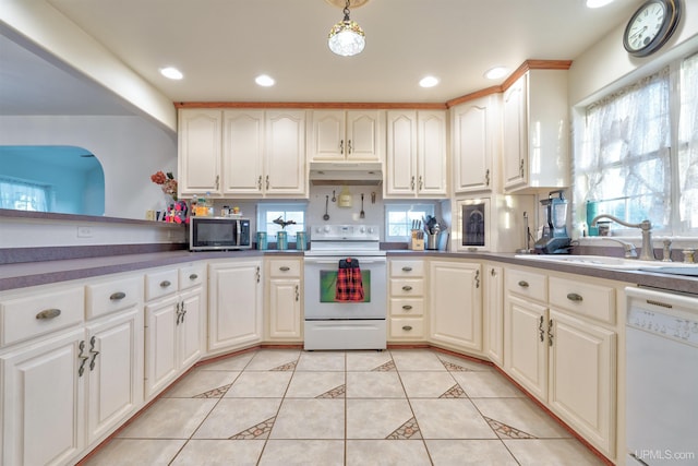 kitchen with light tile patterned floors, white appliances, decorative light fixtures, and sink