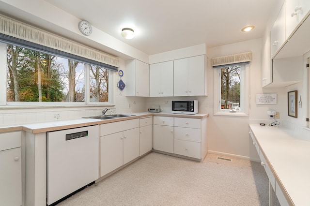 kitchen with white cabinetry, plenty of natural light, white appliances, and sink