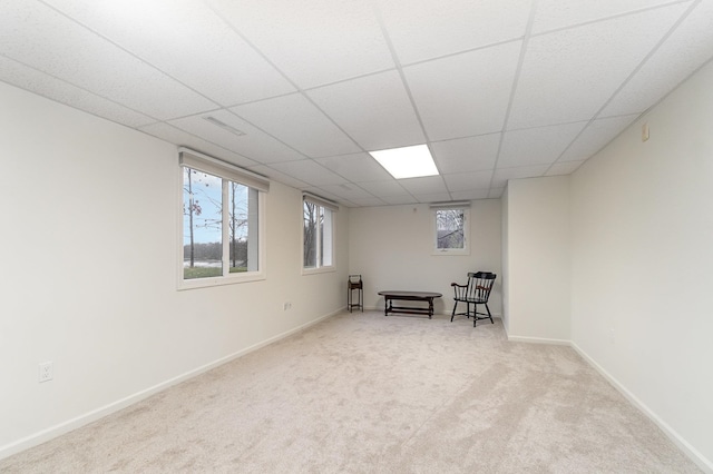 interior space with a paneled ceiling and light carpet