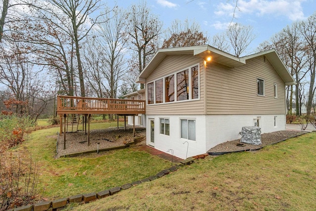 view of side of property with a sunroom, a yard, and a deck