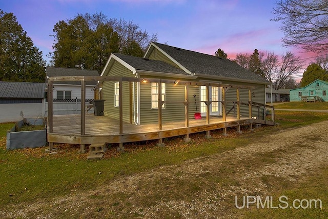 back house at dusk featuring french doors, a yard, and a wooden deck