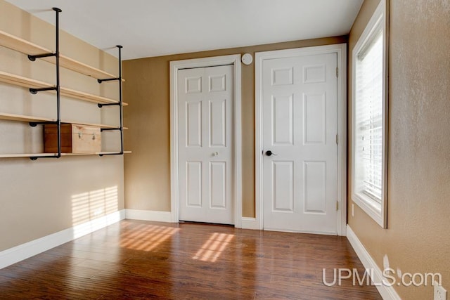 unfurnished bedroom with hardwood / wood-style flooring and multiple closets