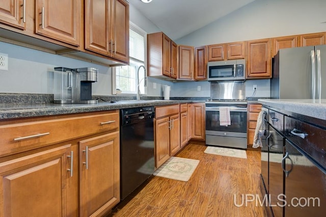 kitchen featuring light wood-type flooring, stainless steel appliances, lofted ceiling, and sink