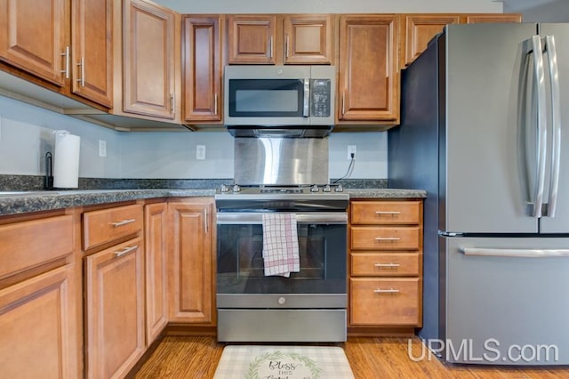 kitchen featuring dark stone countertops, light hardwood / wood-style flooring, and appliances with stainless steel finishes