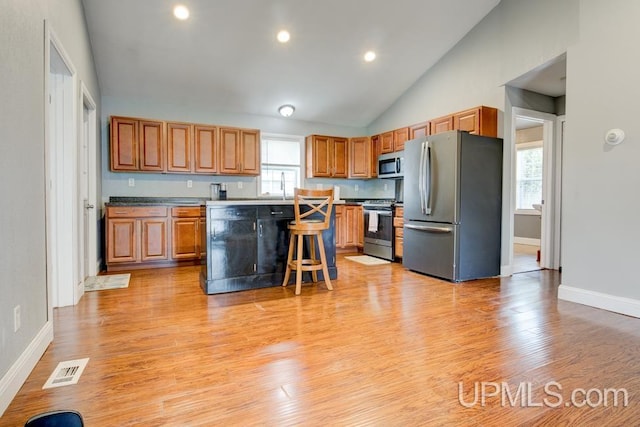 kitchen with plenty of natural light, a kitchen island, light wood-type flooring, and stainless steel appliances