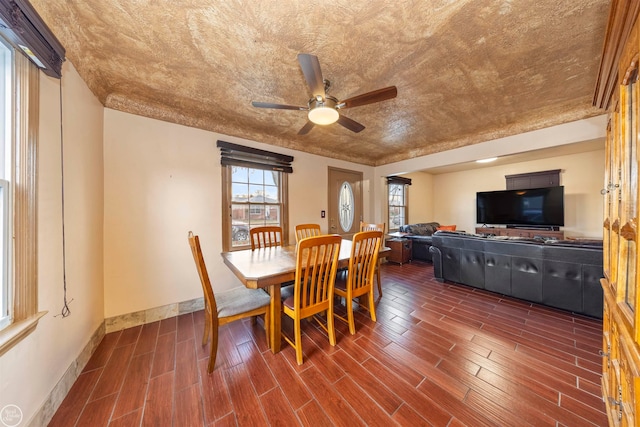 dining area with a textured ceiling, ceiling fan, and dark wood-type flooring