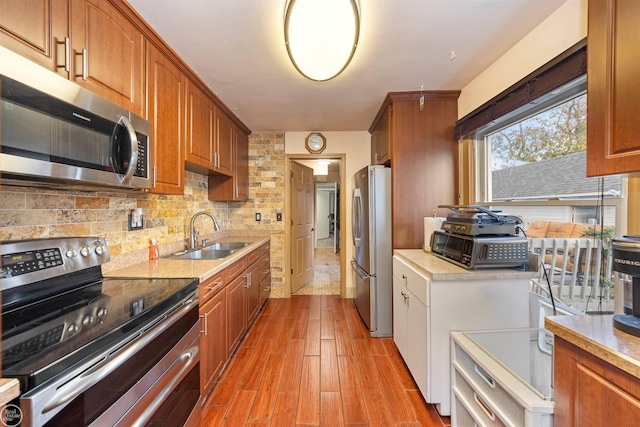 kitchen featuring appliances with stainless steel finishes, tasteful backsplash, light hardwood / wood-style flooring, and sink