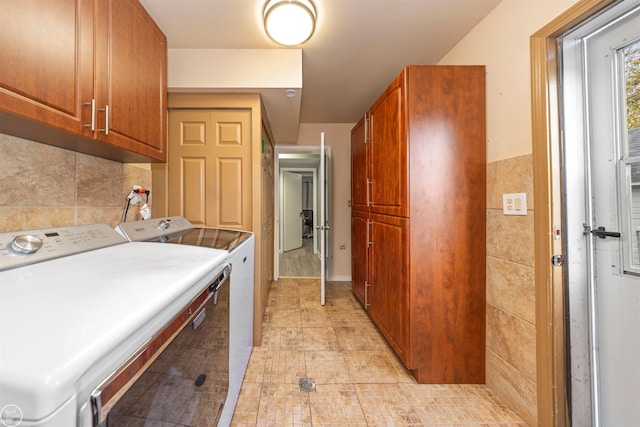 laundry area with washer and clothes dryer, cabinets, light tile patterned floors, and tile walls