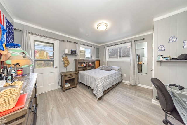 bedroom featuring light hardwood / wood-style floors, crown molding, and multiple windows