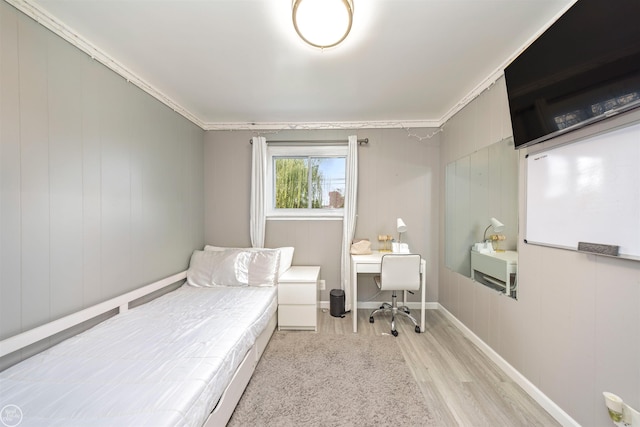 bedroom with wood walls, light hardwood / wood-style floors, and ornamental molding