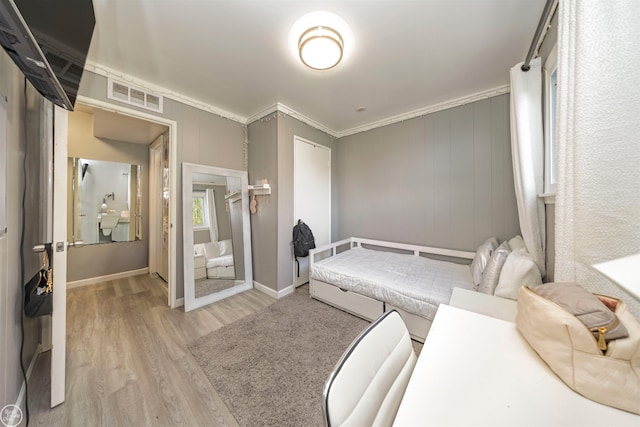 bedroom with light wood-type flooring and crown molding