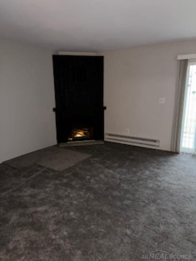 unfurnished room with dark carpet and a baseboard heating unit