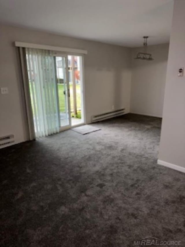 carpeted spare room with a baseboard heating unit