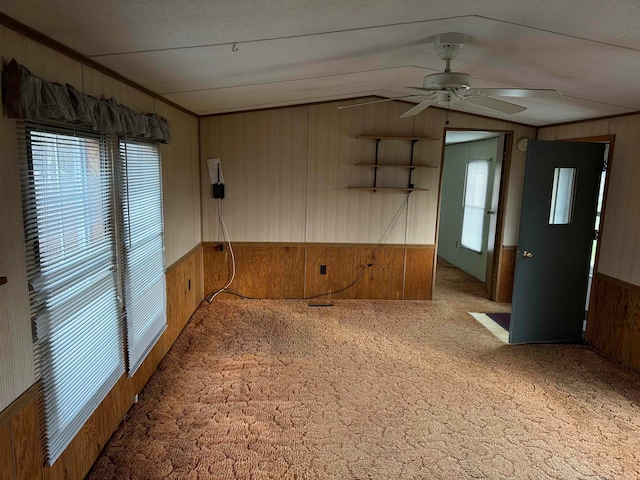 unfurnished room featuring ceiling fan, wood walls, carpet floors, and lofted ceiling