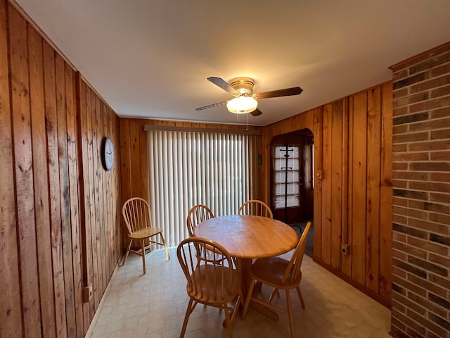 dining room with ceiling fan and wood walls