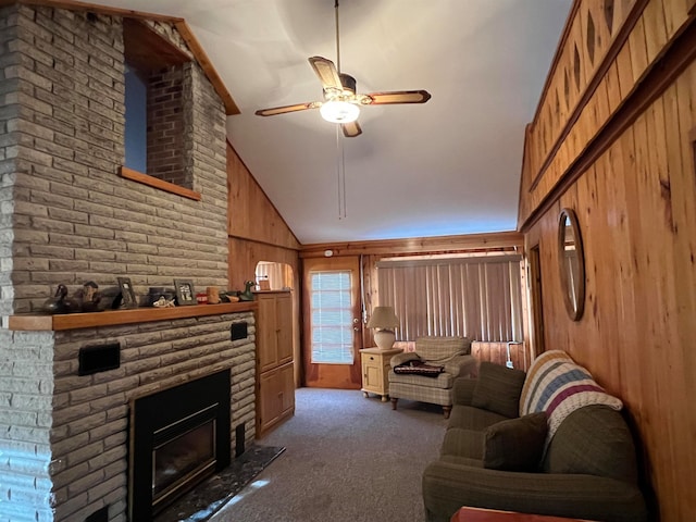 living room featuring dark carpet, high vaulted ceiling, wooden walls, a brick fireplace, and ceiling fan