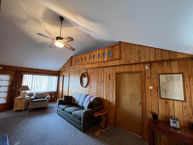 carpeted living room with wood walls, ceiling fan, and high vaulted ceiling