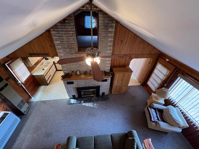 living room with sink, a fireplace, wooden walls, and vaulted ceiling