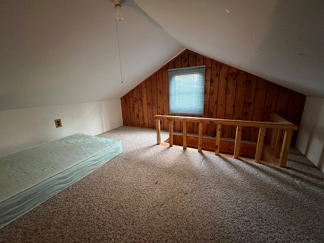 bonus room with carpet floors, wooden walls, and vaulted ceiling