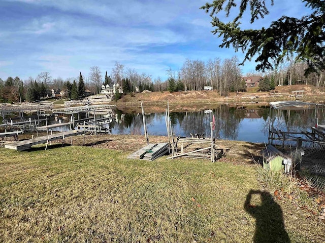 view of dock with a yard and a water view