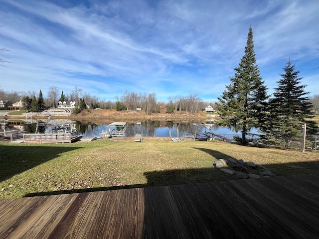 wooden deck featuring a water view, a dock, and a lawn