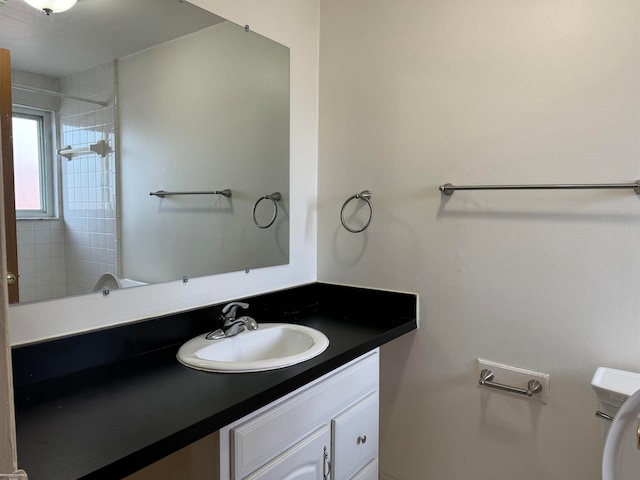 bathroom featuring a tile shower, vanity, and toilet