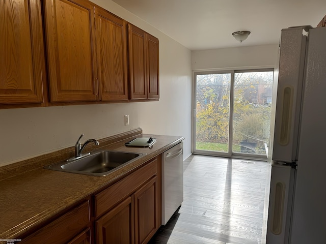 kitchen with dishwasher, white refrigerator, light wood-type flooring, and sink