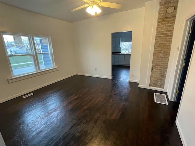 spare room featuring ceiling fan, brick wall, and dark hardwood / wood-style floors