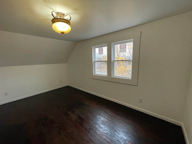 additional living space with dark hardwood / wood-style flooring and vaulted ceiling