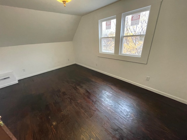 additional living space with dark hardwood / wood-style floors and vaulted ceiling