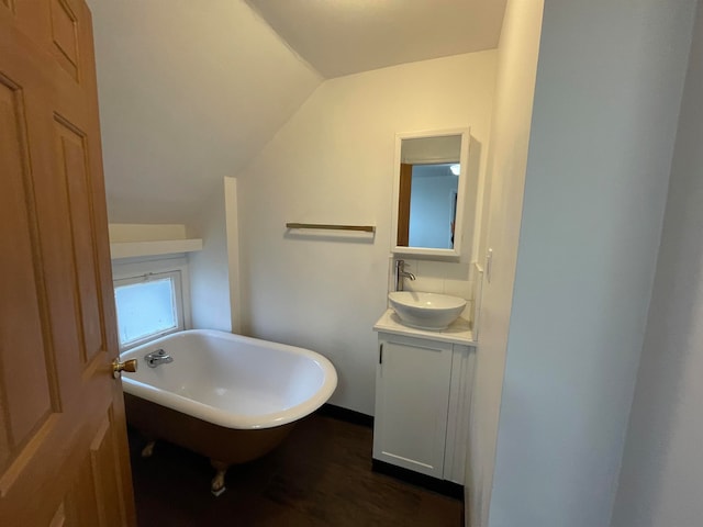 bathroom featuring a bathing tub, vanity, wood-type flooring, and vaulted ceiling