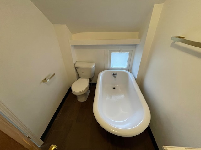 bathroom with hardwood / wood-style floors, a tub to relax in, and toilet