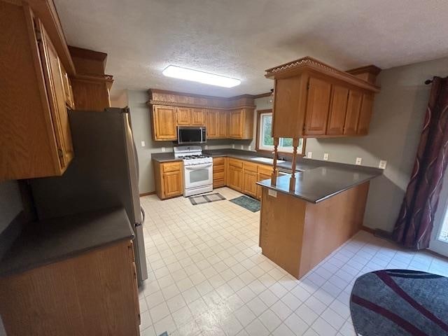 kitchen featuring kitchen peninsula, a textured ceiling, stainless steel appliances, and sink