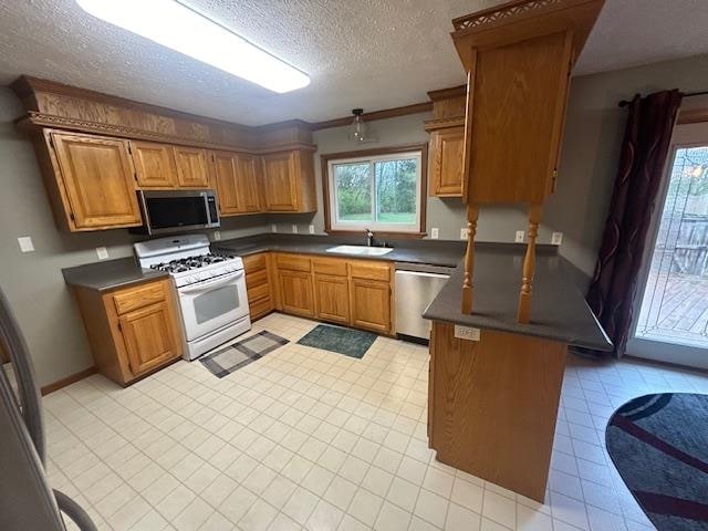 kitchen with a textured ceiling, stainless steel appliances, crown molding, sink, and light tile patterned floors