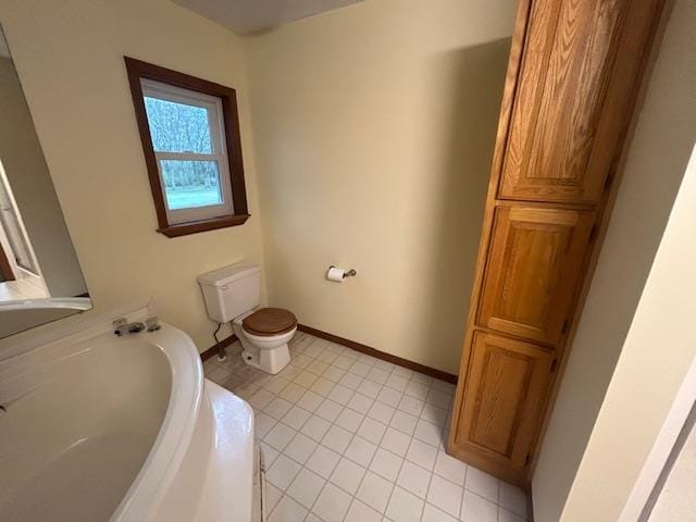 bathroom featuring tile patterned floors, toilet, and a bath