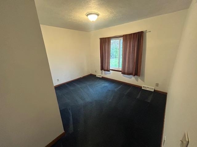 carpeted empty room featuring a textured ceiling